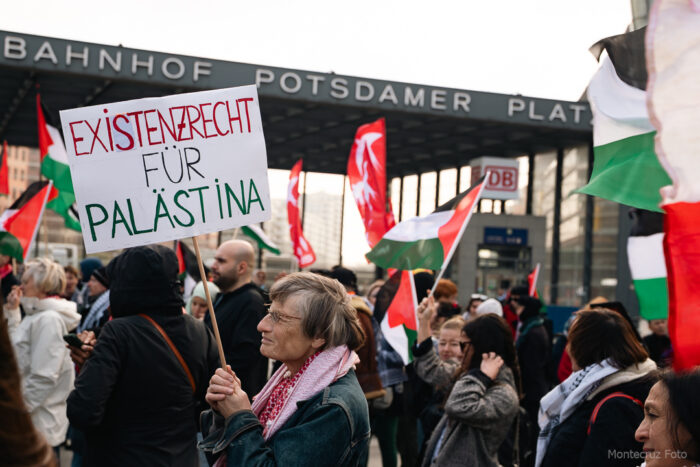 Foto von einer Demonstrantin, die ein Plakat hält mit der Aufschrift "Existenzrecht für Palästina"