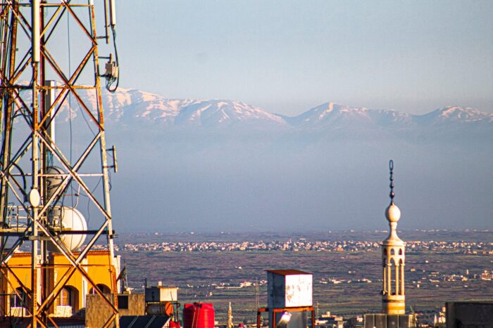 Vor einem Gebirge in Syrien ist eine Stadt und eine Minarette zu sehen.