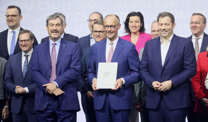 Spitzenpolitiker*innen von CDU und SPD, mittig Friedrich Merz mit dem Koalitionsvertrag in den Händen.
