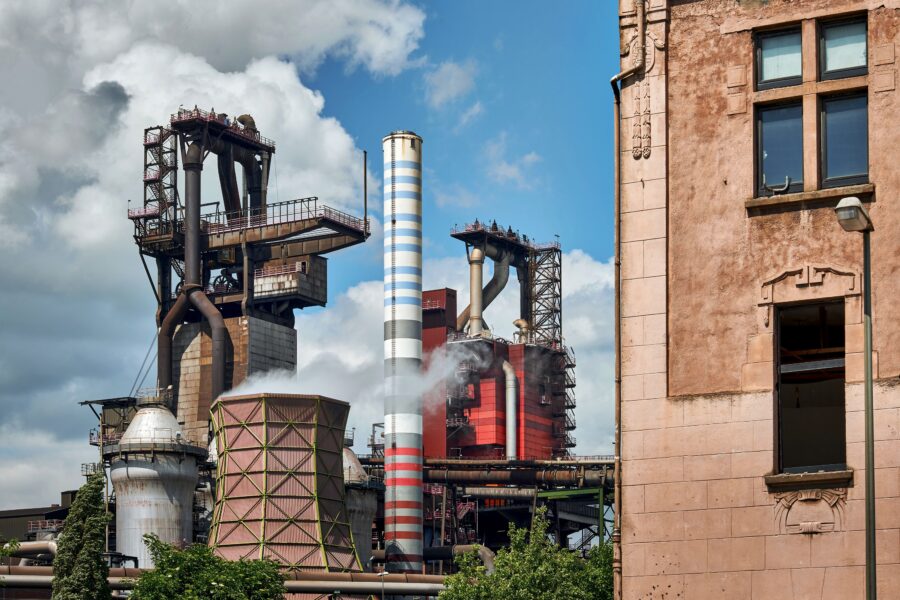 Hochofen und Industrieanage, im Vordergrund sind Teile der Fasssade eines Wohnhauses zu sehen