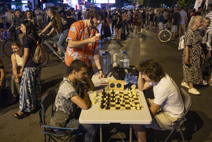 Man sieht Menschen, die während eines Straßenprotestes Schach spielen.