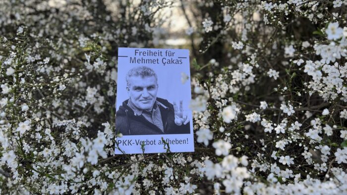 Zu sehen ist eine Blumenwiese, darauf das ausgedruckte Bild von Mehmet Çakas.