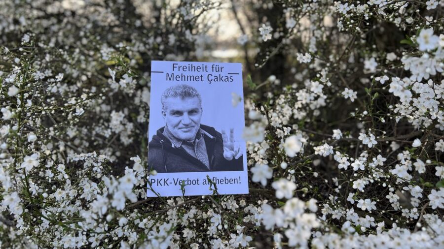 Zu sehen ist eine Blumenwiese, darauf das ausgedruckte Bild von Mehmet Çakas.
