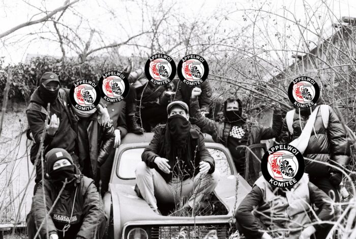 Man sieht eine Gruppe von vermummten Leuten, die auf einem Autowrack sitzen.
