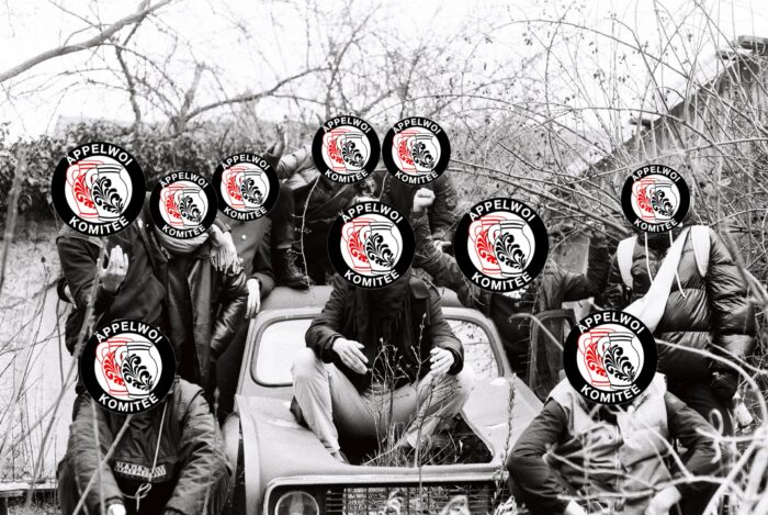 Man sieht eine Gruppe von vermummten Leuten, die auf einem Autowrack sitzen.