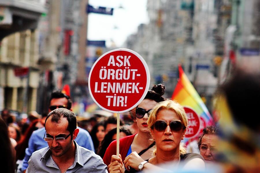 Ein Foto von der Istanbuler Pride 2013. Eine Person hält ein rotes Schild mit der Aufschrift "Ask Örgütlenmektir!" (dt. Liebe ist, sich zu organisieren!).