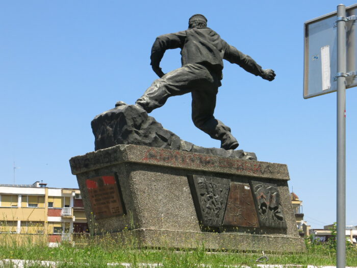 Man sieht ein Denkmal, im Hintergrund Plattenbau.