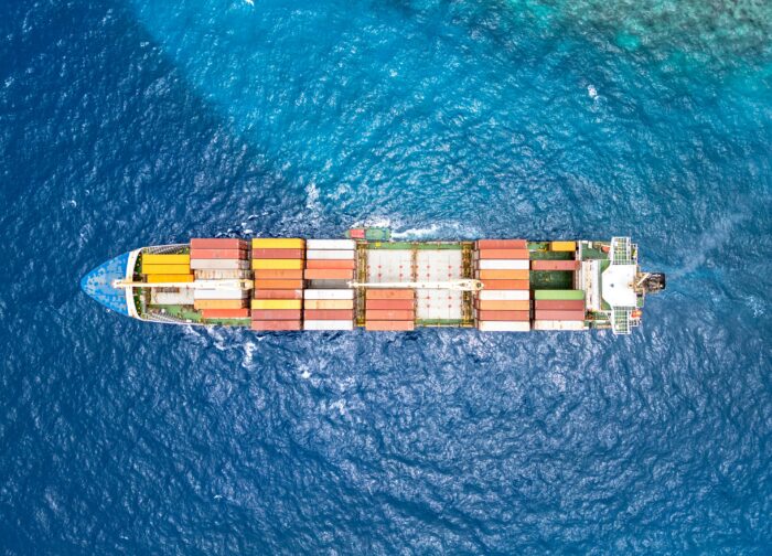 Das Bild zeigt ein Containerschiff von oben, irgendwo im Meer