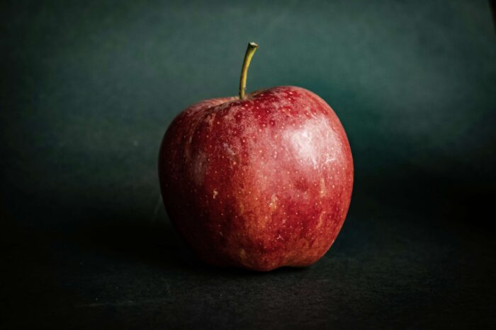 roter Aprfel vor dunkelgrünem Hintergrund