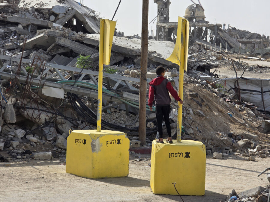 Vor einem Trümmerfeld zwei gelbe Klötze mit Stangen. Auf einem Klotz steht eine Person,