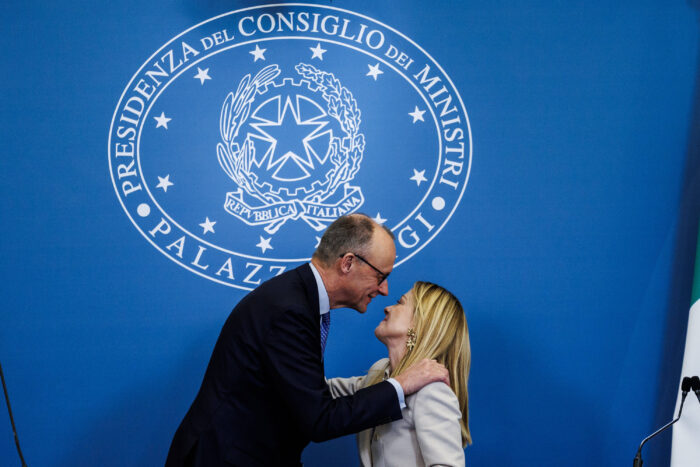 Ein Mann im Anzug und eine Frau im Sacko stehen sich gegenüber, der Mann hat die Arme auf den Schultern der Frau