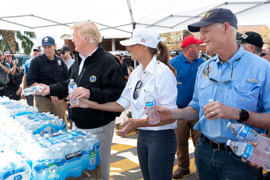 Man sieht Donald und Melania Trump beim Verteilen von Wasserflaschen.