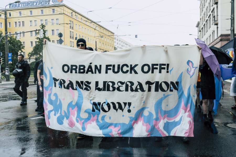 Man sieht ein Transpi, auf dem steht: Orban Fuck Off! Trans Liberation now!