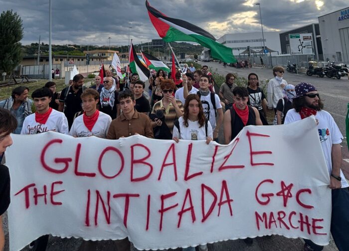 Die Spitze eines Demozuges mit einem weißen Transparen, auf dem steht: Globalize the Intifada.