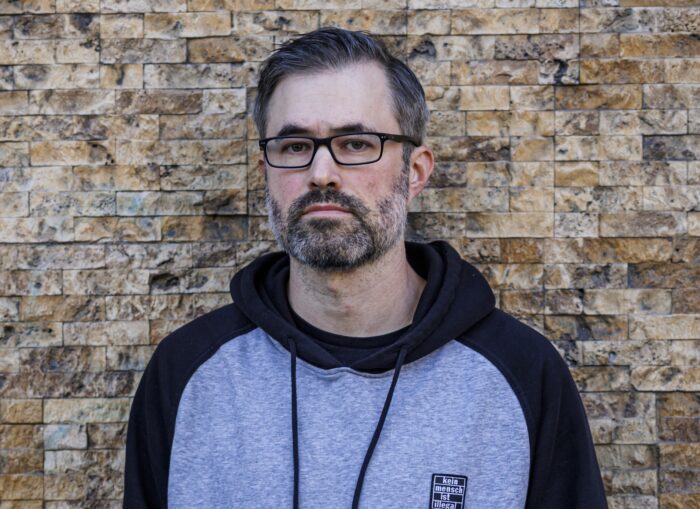 Mark Bray vor einer Backsteinwand