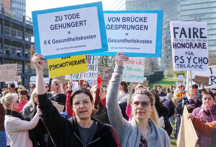 Man sieht Menschen, die Schilder hochhalten.