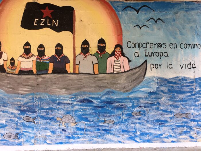 Man sieht ein buntes Mural, das Zapatisten auf einem Boot zeigt.