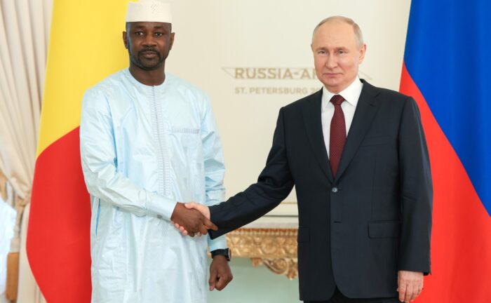 Russlands Präsident Putin und Malis Präsident Goita geben sich die Hand, im Hintergrund die Flaggen beider Länder