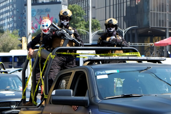 Aufnahme von bewaffneten Männern mit gruseligen Masken, die hinten auf einem Pickup stehen.