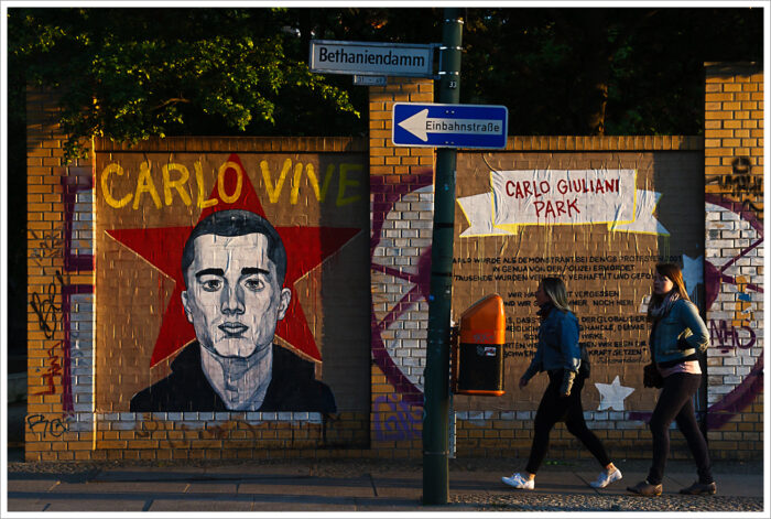Wandbild am Bethaniendamm von Carlo Giulianis Gesicht. Darüber steht geschrieben "Carlo Vive", daneben eine Beschreibung dessen, wie er ermordet wurde.