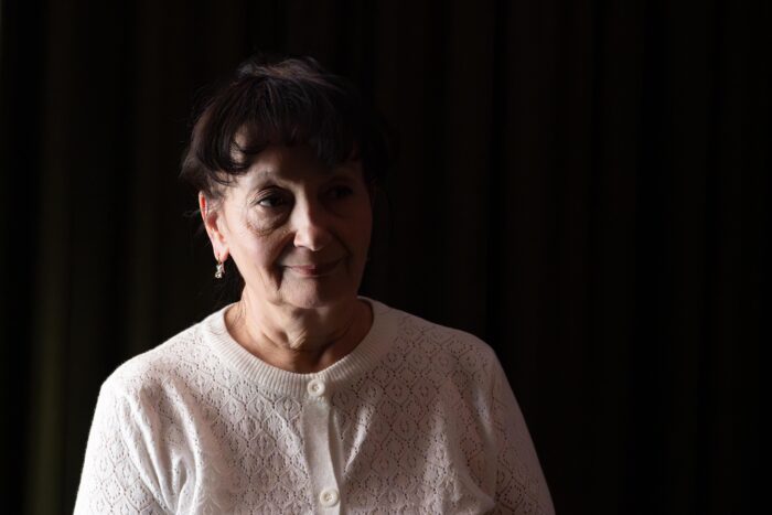 Eine Frau vor dunklem Hintergrund, die linke Gesichtshälfte liegt im Schatten