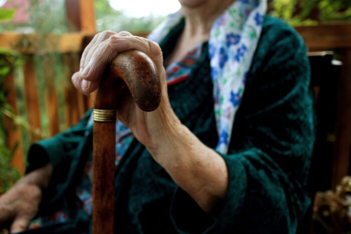 Die Hand einer alten Frau hält einen Gehstock