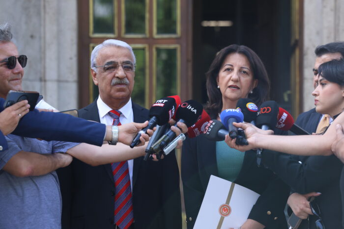Abgeordnete der linken DEM-Partei, Mithat Sancar und Pervin Buldan, sprechen zur Presse. Um sie herum sind Reporter*innen, die ihnen Mikrofone entgegenhalten.