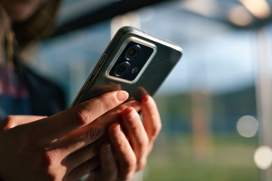 Die Hände einer Peron halten ein Handy.