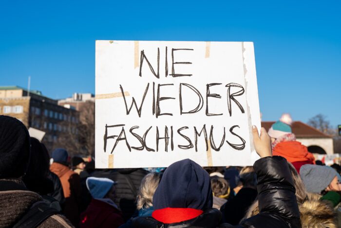 Demonstrant hält eiin Plakat mit der Aufschrift "Nie wieder Faschismus" hoch