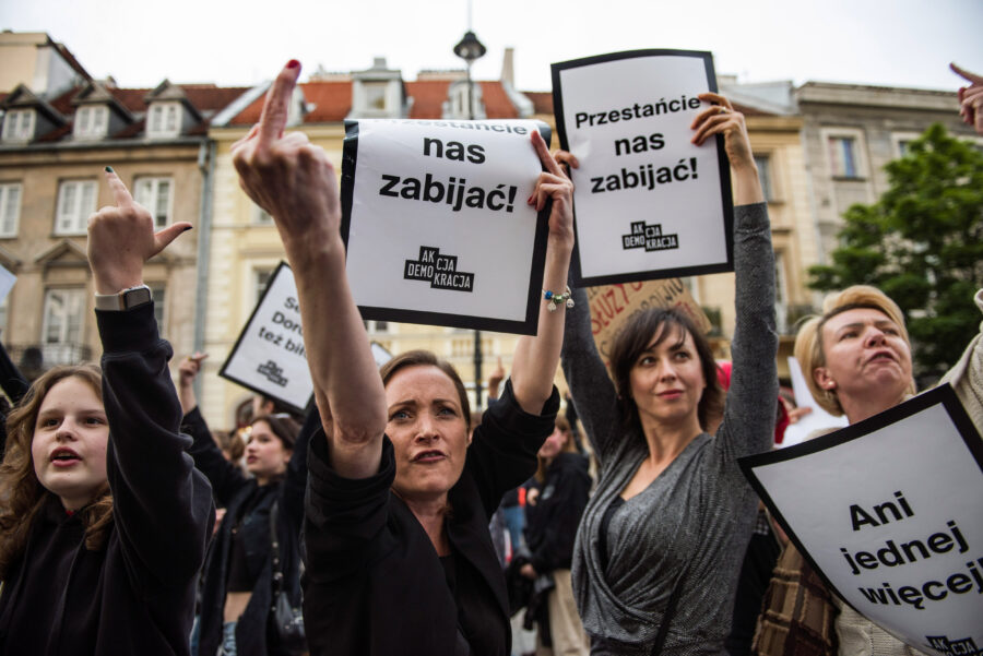 Demonstrierende Frauen halten Plakate und Mittelfinger in die Luft