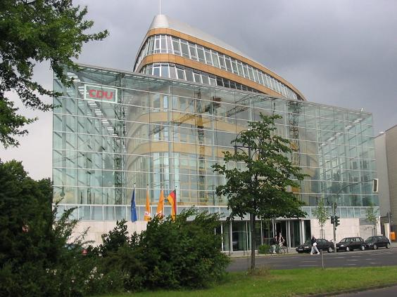 Im Vordergrund links Bäume und Büsche, daneben und dahinter die Parteizentrale der CDU in Berlin.