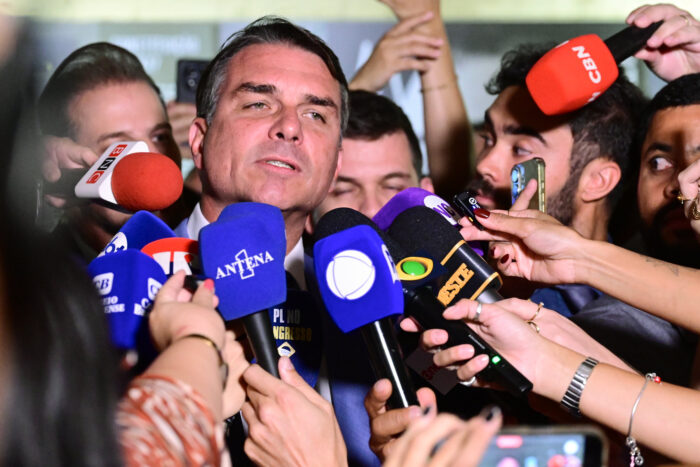 Das Bild zeigt den Präsidentschaftskandidaten Flavio Bolsonaro, umringt von Journalist*innen, die ihm Mikrofone vors Gesicht halten. Er spricht in eines.
