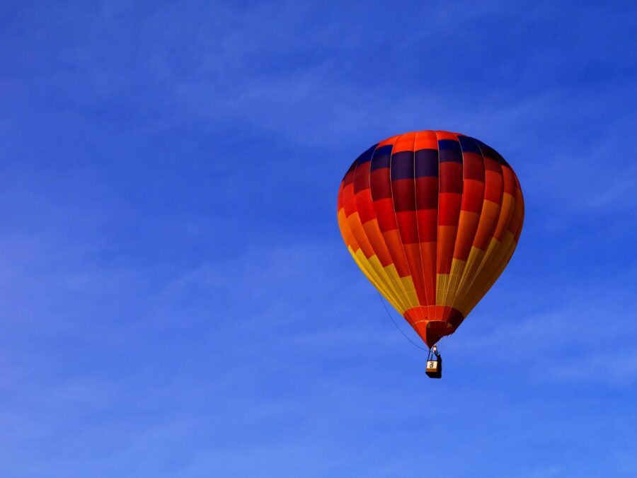 Man sieht einen mehrfarbigen Heißluftballon am Himmel.