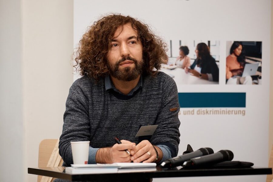 Man sieht eine Person an einem Tisch sitzen.