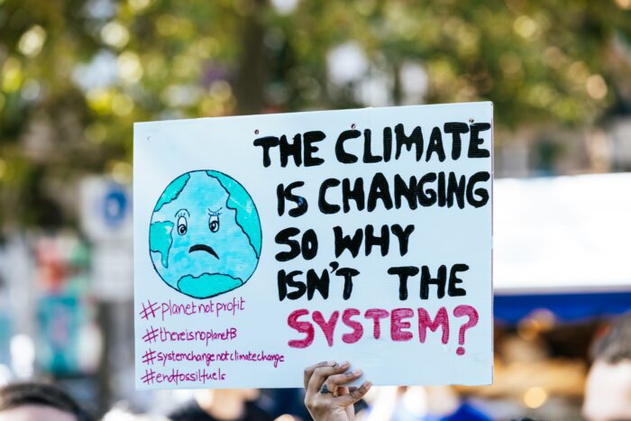 Demoplakat mit der Aufschrift: "The Climate is changing so why isn't the system?